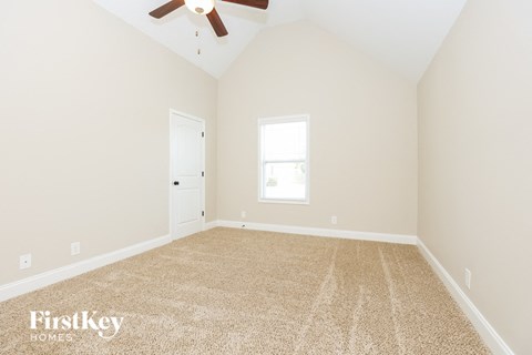 the spacious living room with carpet and a ceiling fan