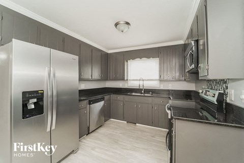 A modern kitchen with a stainless steel refrigerator and wooden flooring.