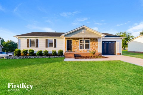 A house with a well-maintained lawn and a clear sky in the background.