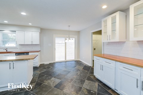 A kitchen with white cabinets and a wooden counter top.
