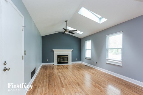 A spacious room with a fireplace and a ceiling fan.