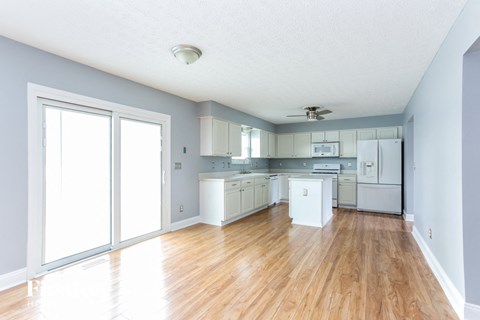 A kitchen with white appliances and wooden floors.