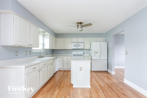 A kitchen with white cabinets and a white fridge.