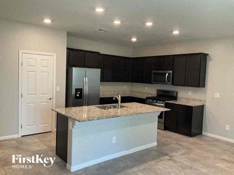 A kitchen with granite countertops and dark brown cabinets.