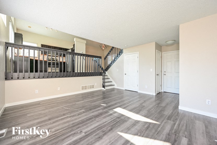 an empty living room with wood floors and a staircase