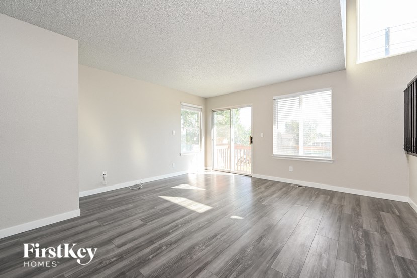 an empty living room with wood flooring and a door to a balcony