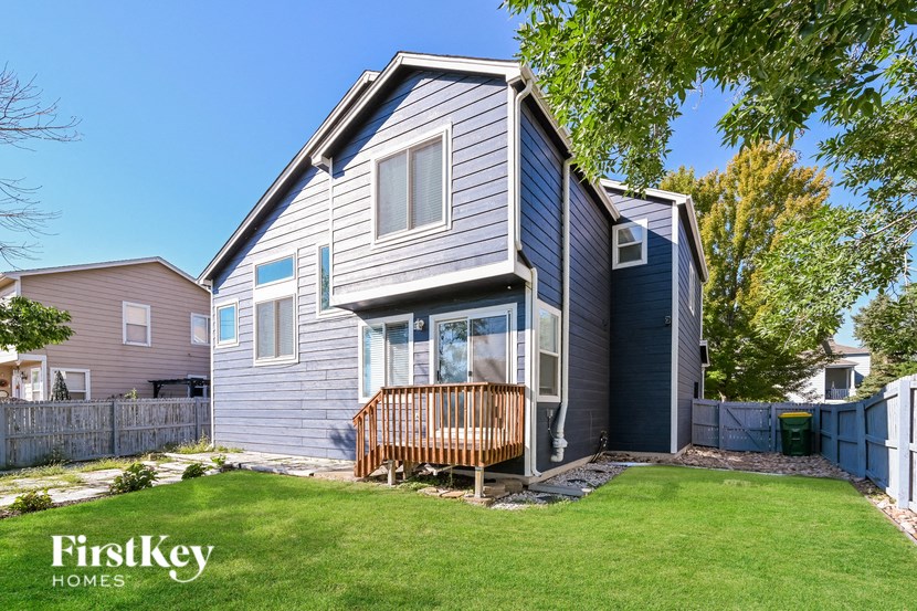 a blue house with a wooden deck in the yard