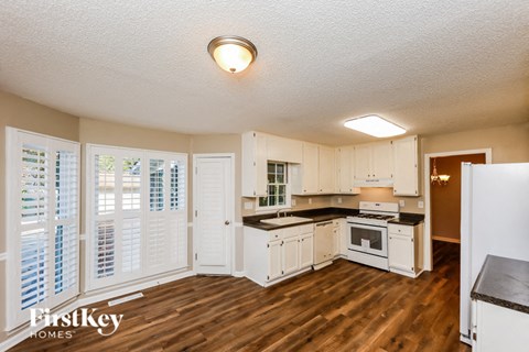 A kitchen with white cabinets and a wooden floor.