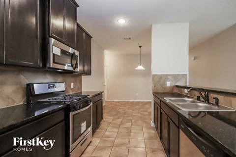 A kitchen with black cabinets and a stove top oven.