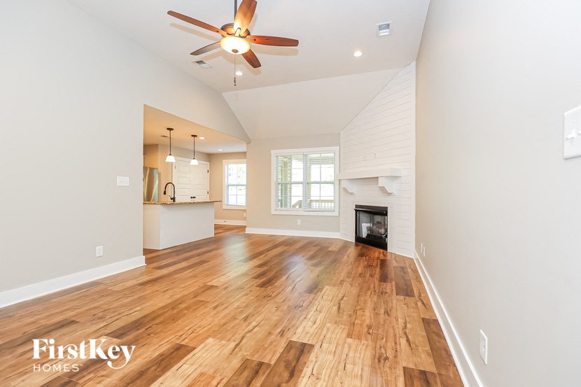 an empty living room with a fireplace and a ceiling fan