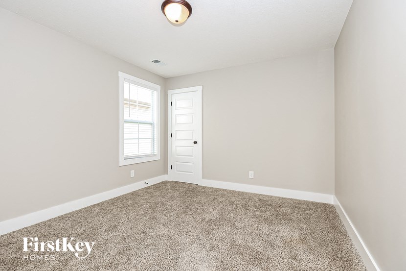 a bedroom with a carpeted floor and a white door and window