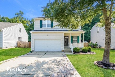 a white house with a white garage door and a tree