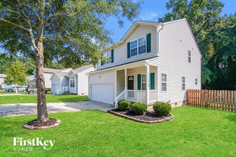 a white house with green shutters and a tree in the front yard