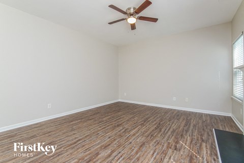 the living room of an empty house with wood flooring and a ceiling fan