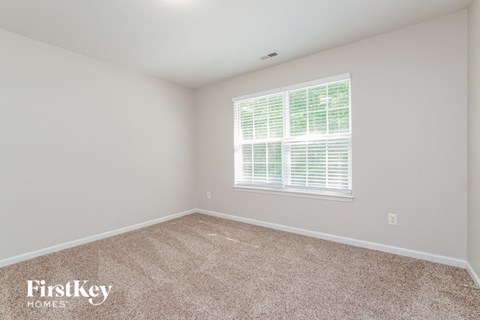 a bedroom with carpet and a large window