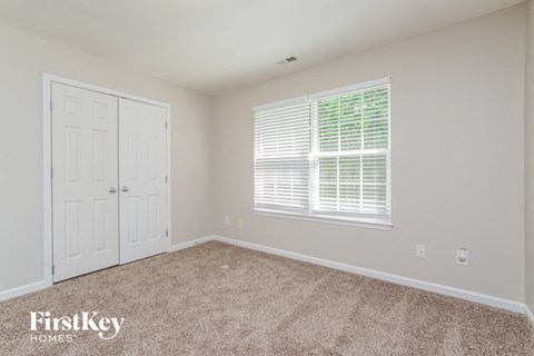 a bedroom with carpet and a door and a window