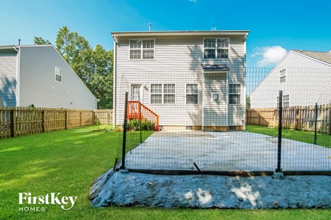the backyard of a white house with a pool and a fence