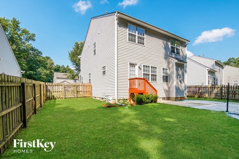 a backyard with a white house and a wooden fence