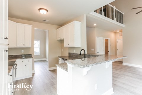 A kitchen with white cabinets and a marble countertop.