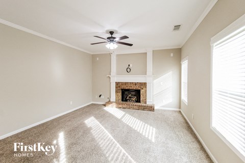 A spacious living room with a fireplace and a ceiling fan.
