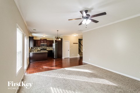 A spacious living room with a ceiling fan and a rug on the floor.