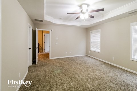 A spacious room with a ceiling fan and carpeted floor.