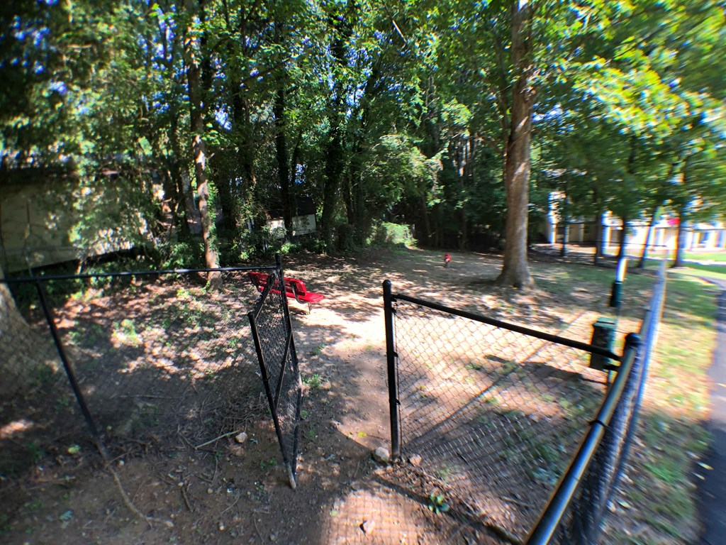 the dog park is behind a fence and trees