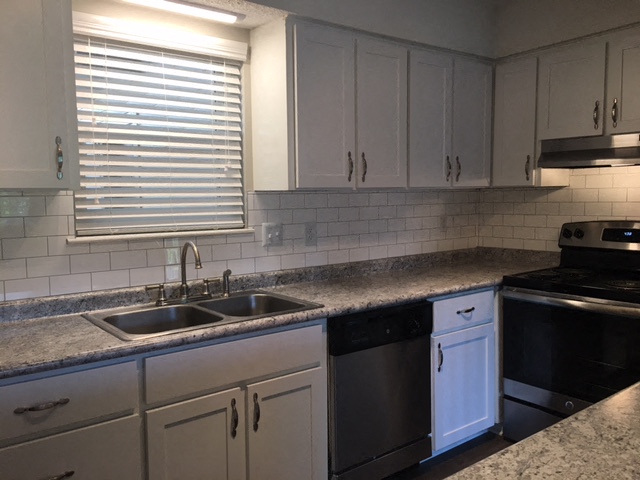 a kitchen with white cabinets and a sink and a window