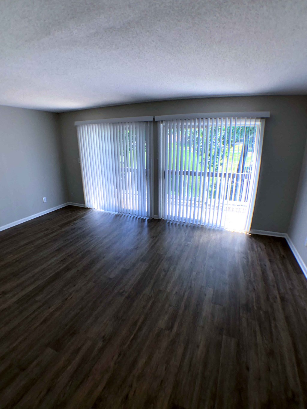an empty living room with wood floors and a window