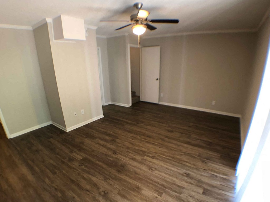 an empty living room with wooden floors and a ceiling fan