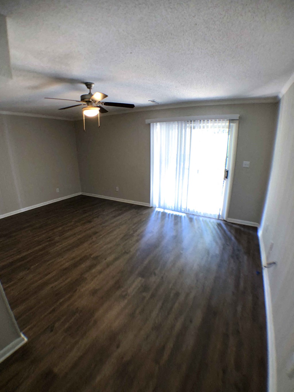 an empty living room with wood floors and a ceiling fan