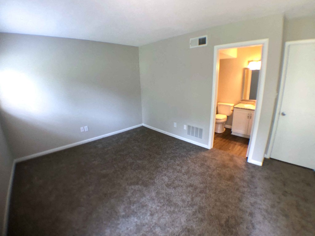a empty room with a carpeted floor and a door to a bathroom