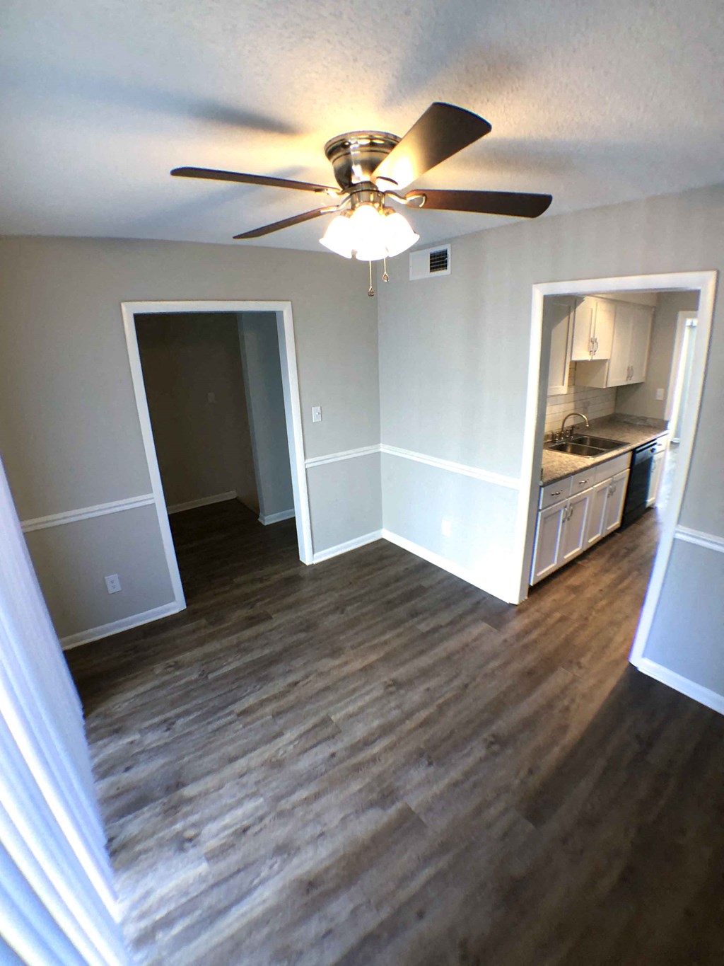 a renovated living room with a ceiling fan and a kitchen