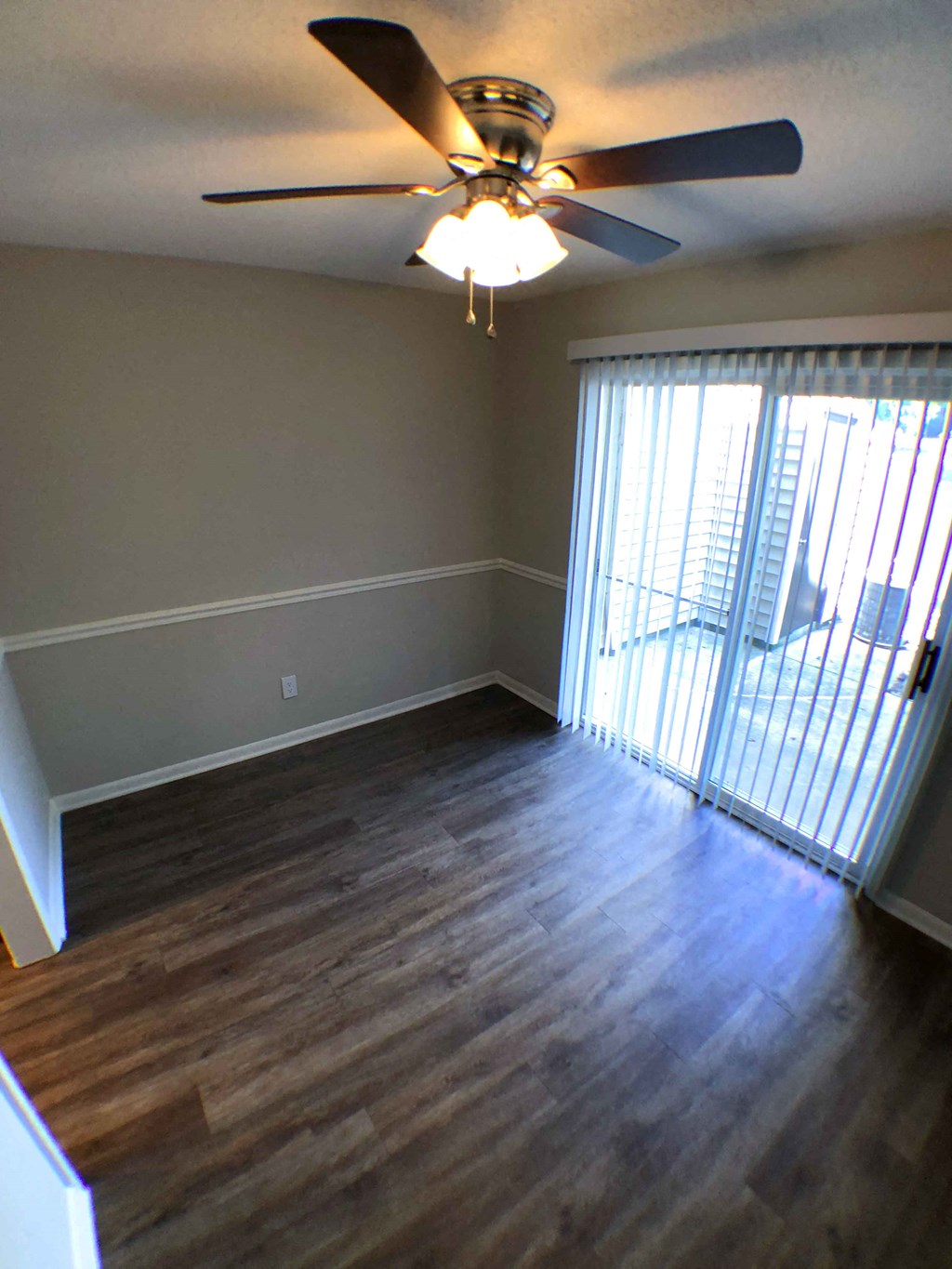 an empty living room with a ceiling fan and a window