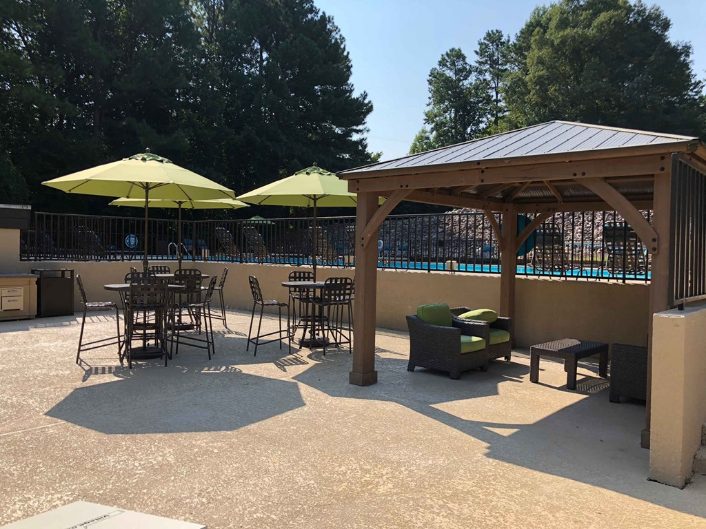 a patio with tables and chairs and umbrellas next to a pool