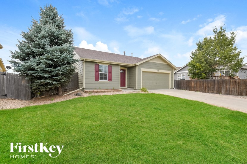 A house with a green lawn and a tree in front of it.