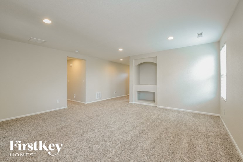 A spacious empty room with a carpet floor and a fireplace.