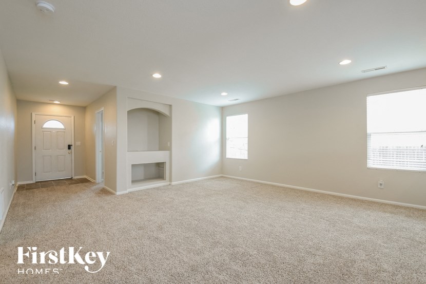 A spacious room with a carpeted floor and a window on the right side.