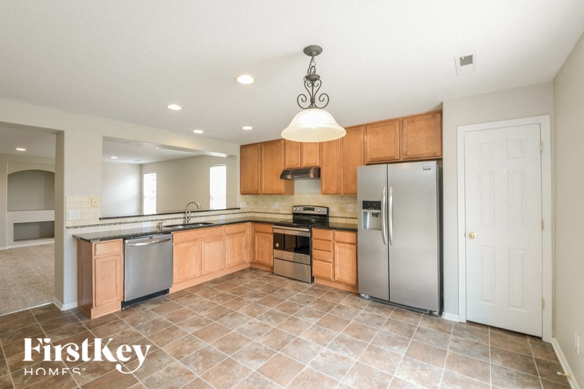 A kitchen with a tile floor and a refrigerator.