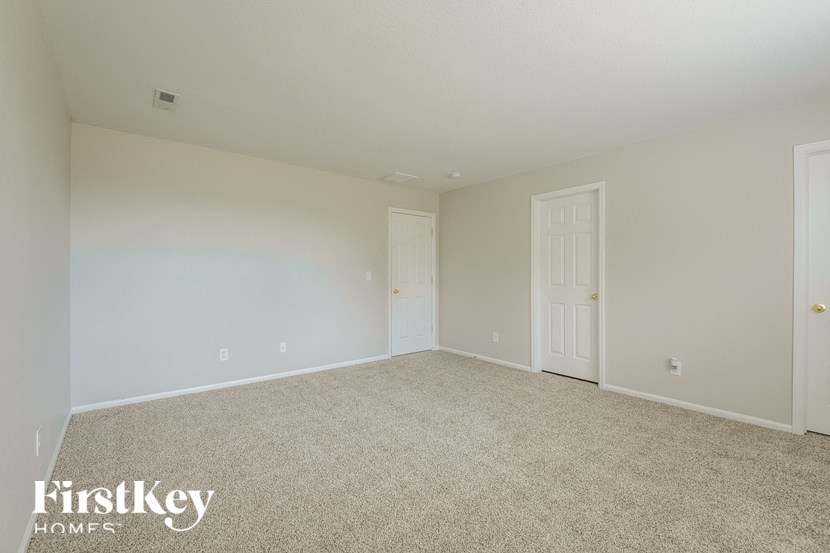 A room with a carpeted floor and two doors.