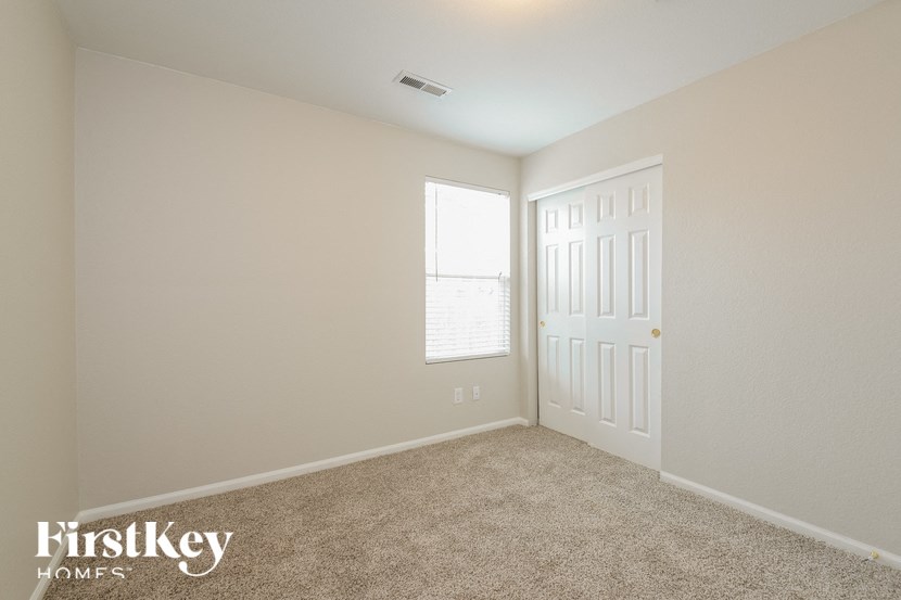 A room with a carpeted floor, a door, and a window with blinds.