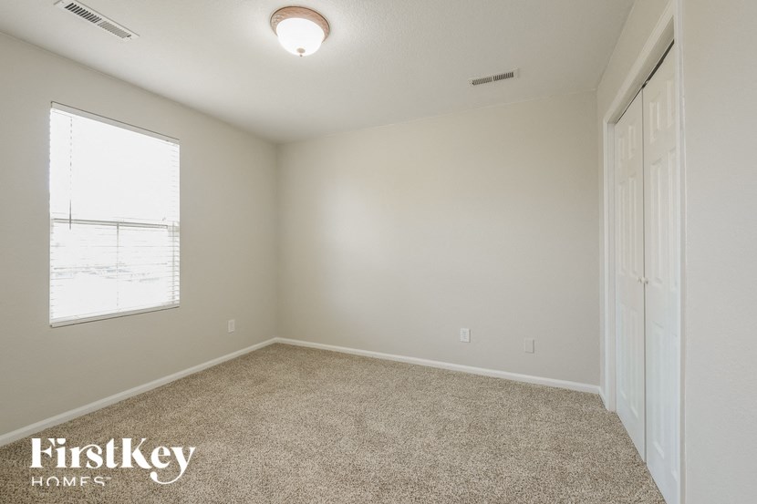 A room with a carpet floor and a window with blinds.