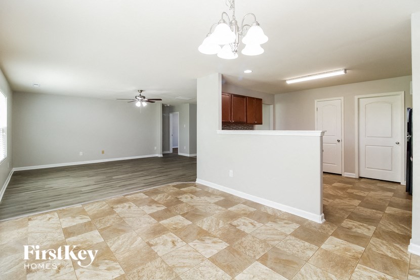 an empty living room with a white wall and a kitchen