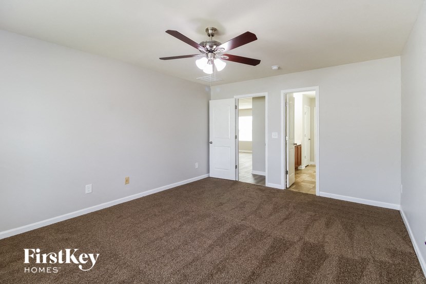 an empty living room with a ceiling fan and carpet