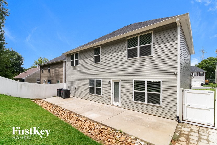 a small gray house with a driveway and a lawn