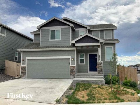 a gray house with a blue door and a driveway