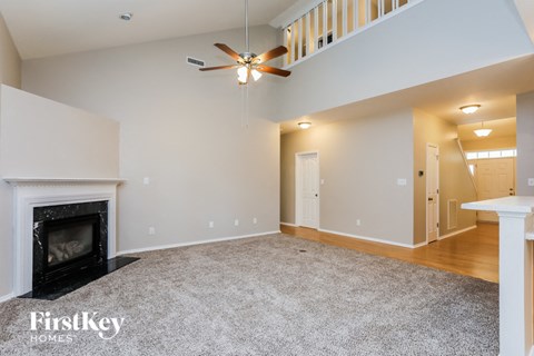A spacious living room with a fireplace and a carpet on the floor.