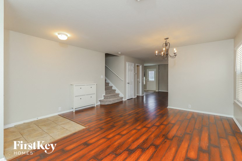 the living room and dining room with wood flooring and white walls
