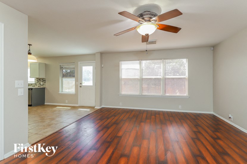 an empty living room with wood floors and a ceiling fan