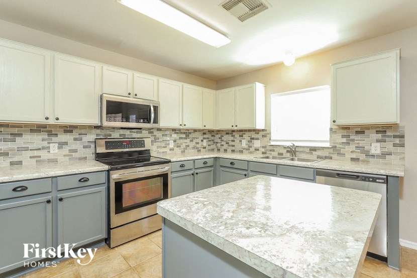 a kitchen with white cabinets and granite counter tops and stainless steel appliances